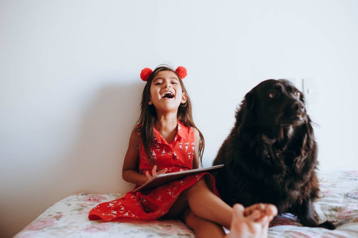 a girl and a dog sitting on a bed
