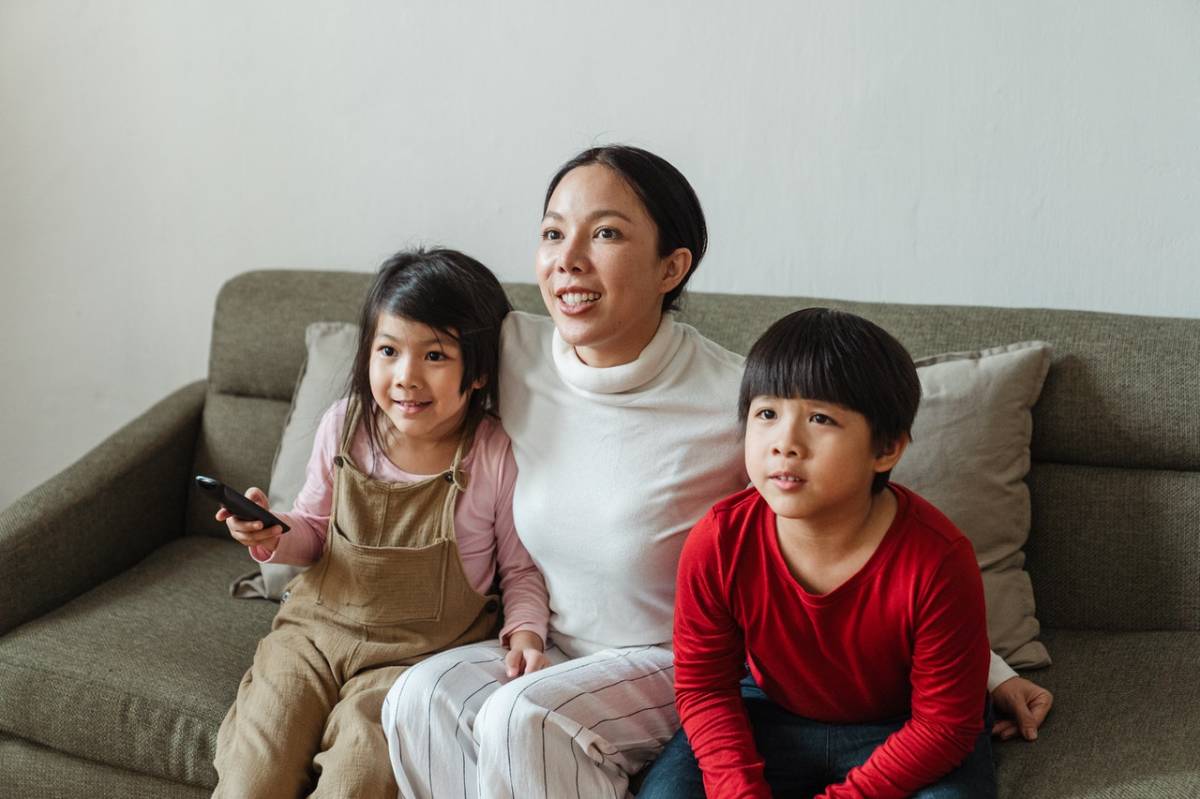 a mother and two kids watching television